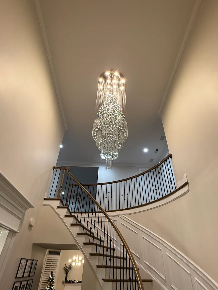 Crystal chandelier installation in grand foyer staircase